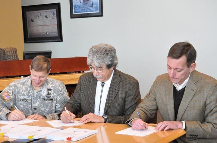Three people signing papers to help The Tulalip Tribes establish the first Native American aquatic resource program of its kind in the nation